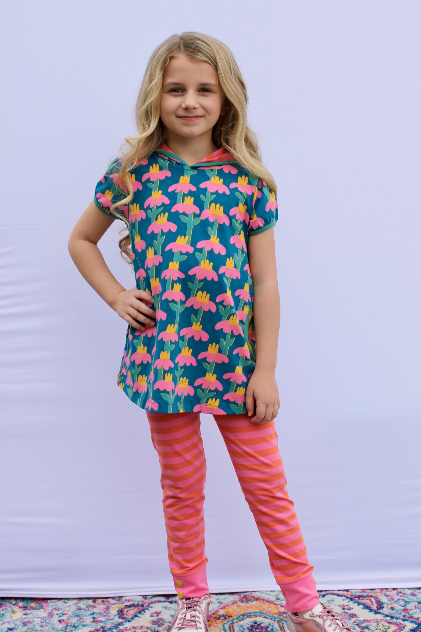 Finding Foxtale Chasing Daisies tunic with hood and pockets, paired with striped leggings featuring button accents at the ankles.