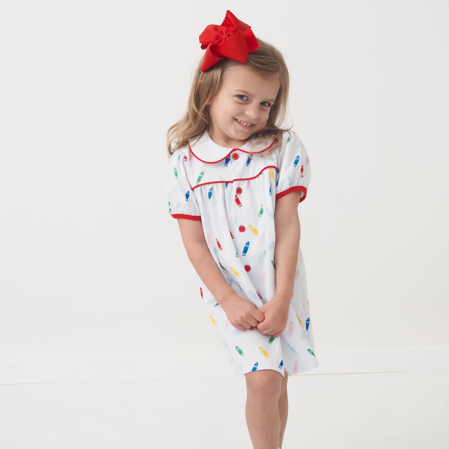 Girls back to school dress with colorful crayon and apple print, button-down front, and collared neckline, made from soft cotton spandex blend.