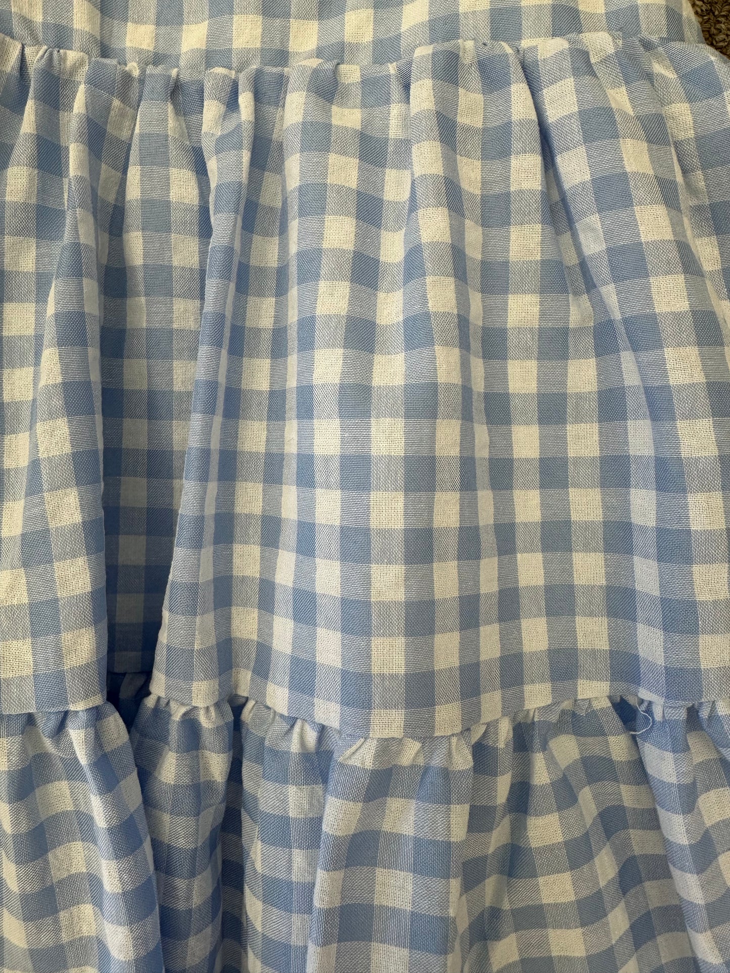 Toddler wearing a blue gingham spaghetti strap dress, lightweight and comfortable for warm weather.