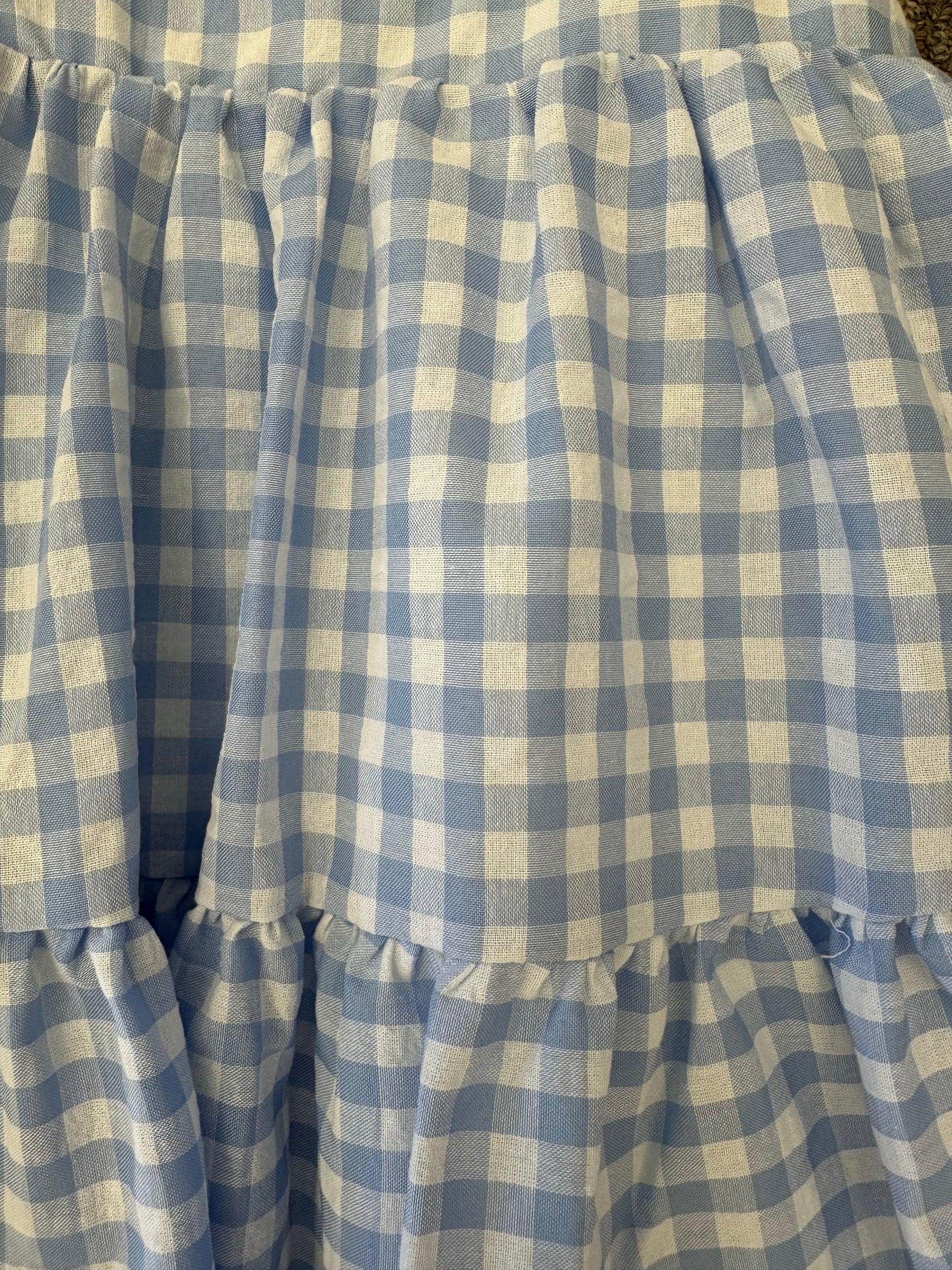 Toddler wearing a blue gingham spaghetti strap dress, lightweight and comfortable for warm weather.