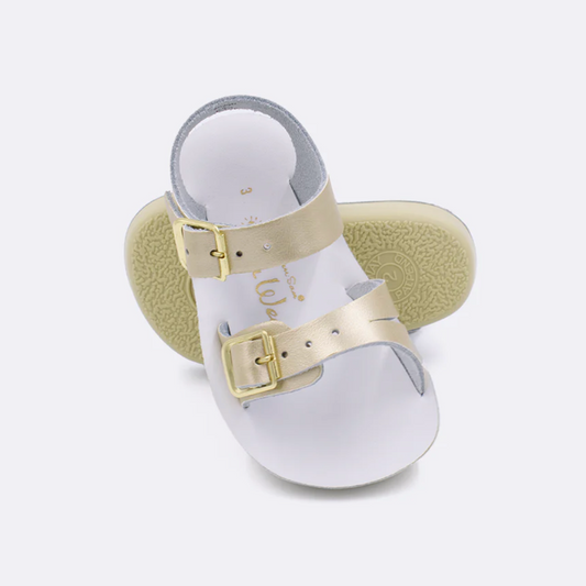 Infant gold leather sandal with adjustable buckles and flexible sole, water-friendly and soft for baby’s first steps.