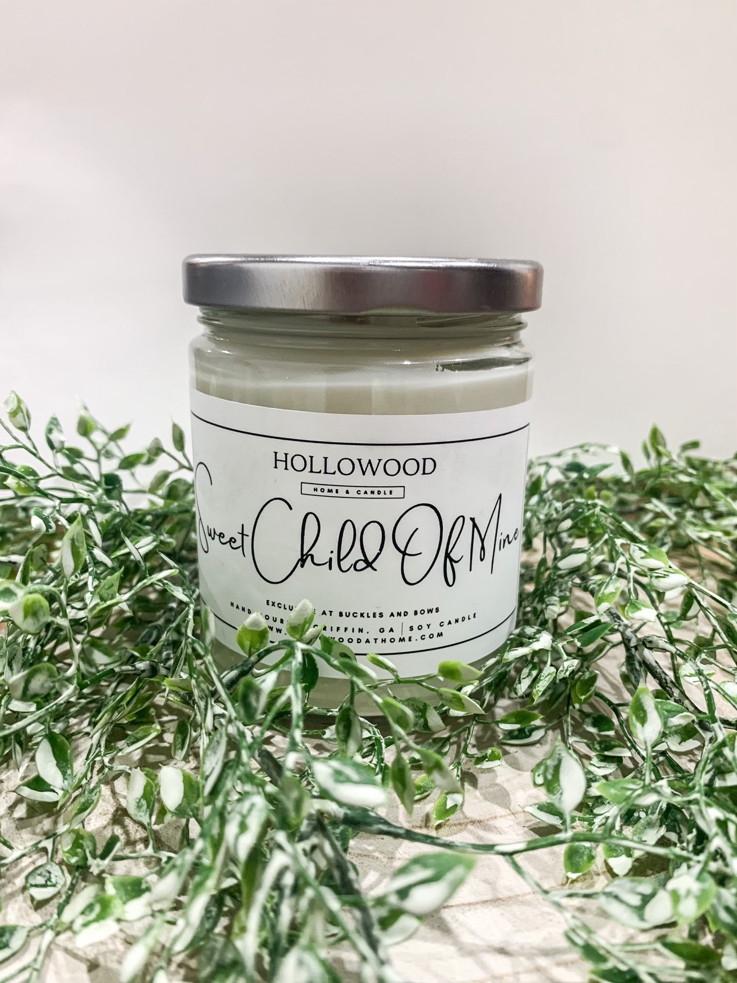 Exclusive Buckles & Bows candle in clear glass jar with black lid, available in mini, 8 oz, and 13 oz sizes, custom-made by Hollywood at Home.